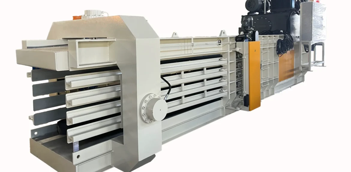 a large industrial baler, designed for full automatic operation with a capacity of 100 tons. This machinery is typically used for compressing waste materials into compact bales, which simplifies handling and transportation. The baler shown in the image is predominantly gray with white and orange accents, and it includes multiple compression chambers and hydraulic mechanisms to ensure efficient baling of materials. This type of equipment is crucial in waste management and recycling facilities to reduce the volume of waste and improve the efficiency of recycling processes.