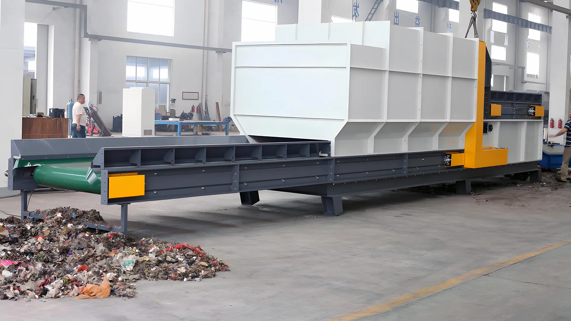 Large industrial air separator for plastic recycling with a conveyor belt and waste material, situated in a factory environment.