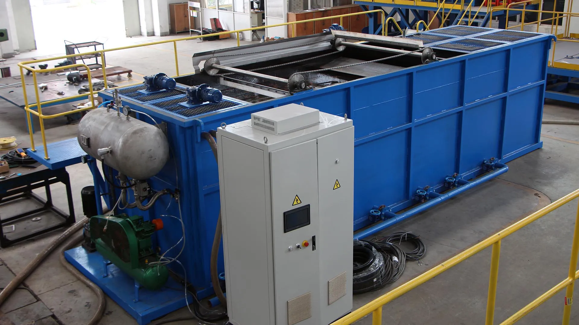 Dissolved Air Flotation (DAF) system in a plastic recycling facility, featuring a large blue tank with metal components and an adjacent control panel.