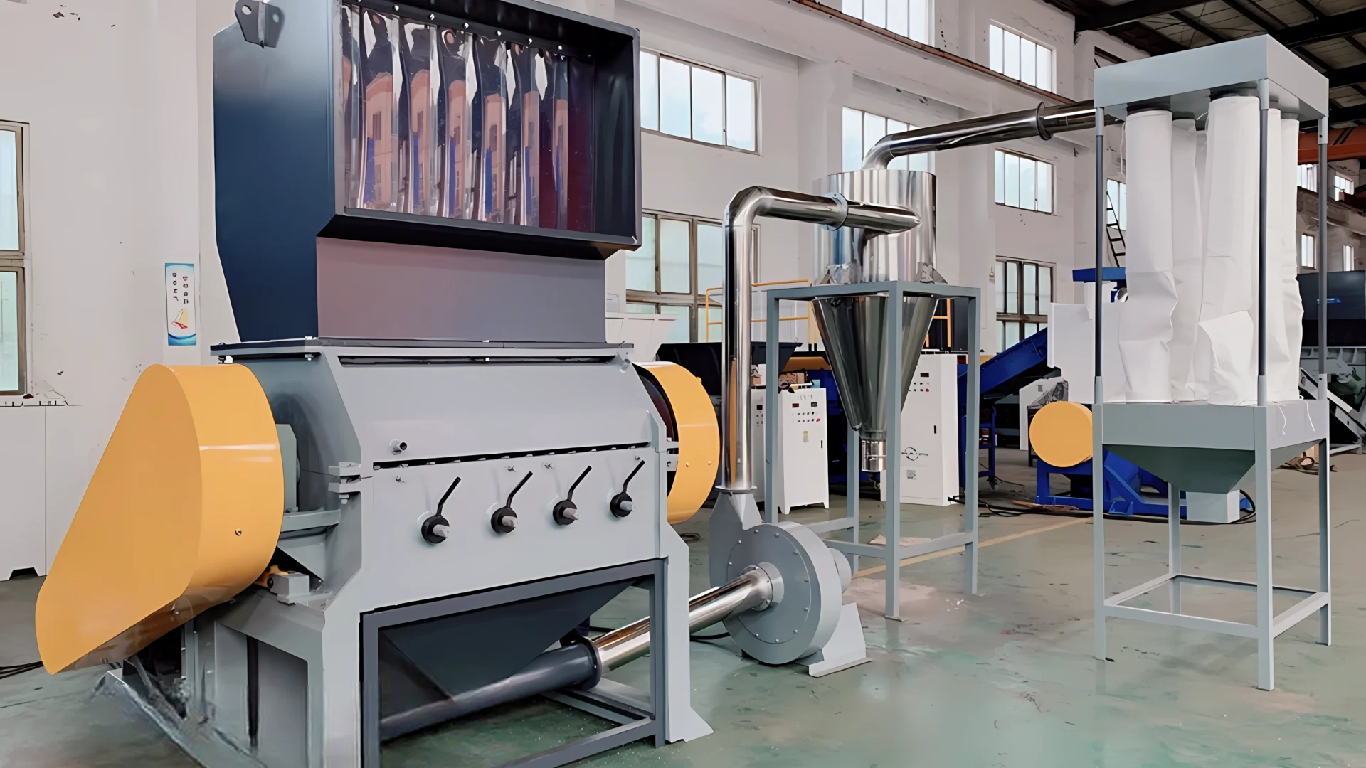 a setup of extra large rigid plastic granulator machines. This setup includes several components: a feed system, granulators, and possibly sorting or collection mechanisms. The granulators are designed to handle substantial volumes of plastic, breaking them down into smaller, manageable sizes for recycling purposes.