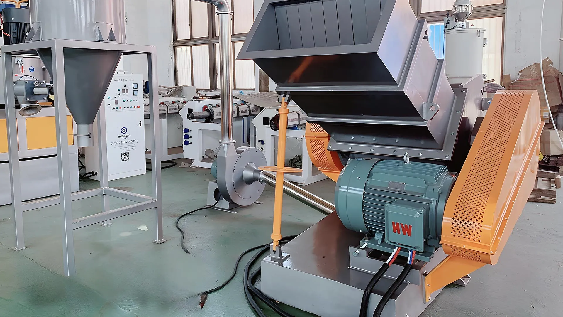 Extruded plastic granulator machine with an extended inlet and robust motor in an industrial setting, used for recycling rigid plastics like pipes, sheets, and boards.