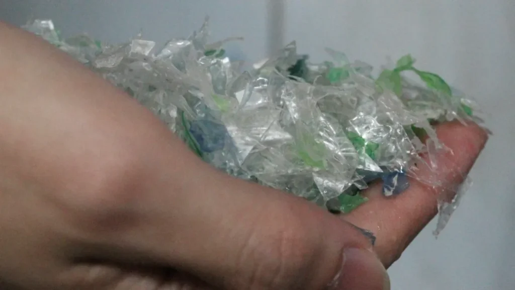 Hand hält bunten zerkleinerten Plastikmüll