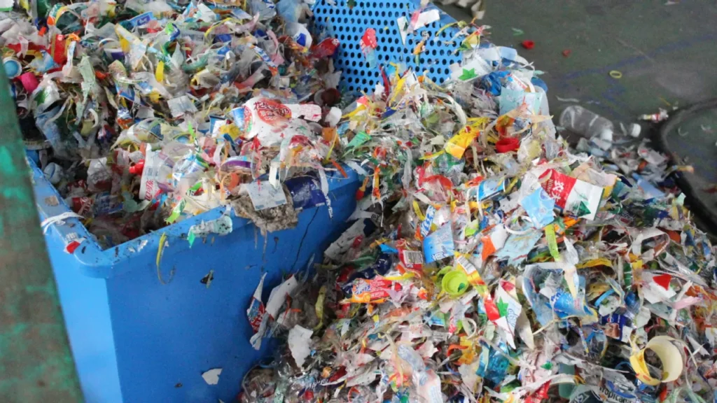 Mixed shredded plastic waste in blue recycling bins