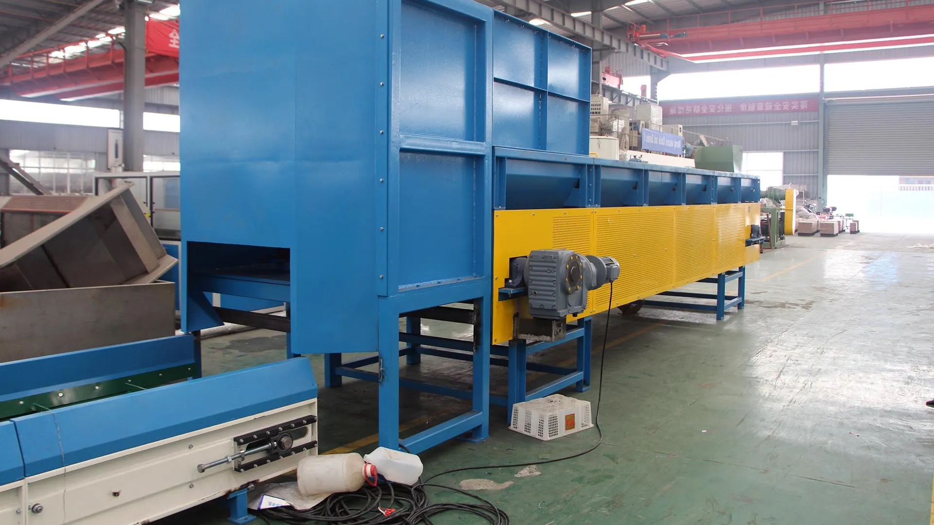 Blue and yellow vertical debaler machine in an industrial warehouse setting.