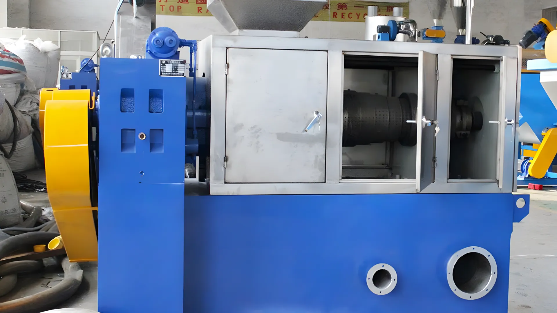 a screw press dewatering machine, specifically designed for processing PE films. The machine has a robust, industrial design, with a prominent blue and yellow color scheme. It features a vertical feeder at the top where the plastic material is fed into the machine, and a horizontal screw press mechanism is housed within a metal casing. The casing has a few doors, one of which is open, revealing the internal screw shaft and outer tube with perforations for water drainage. The overall build suggests heavy-duty usage for efficient moisture removal in plastic recycling or similar industrial processes.