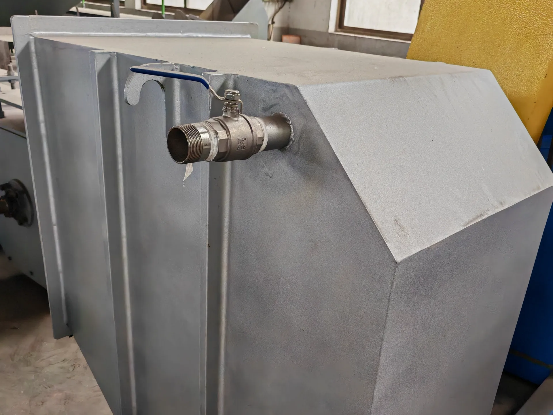 Large gray industrial tank with protruding metal faucet